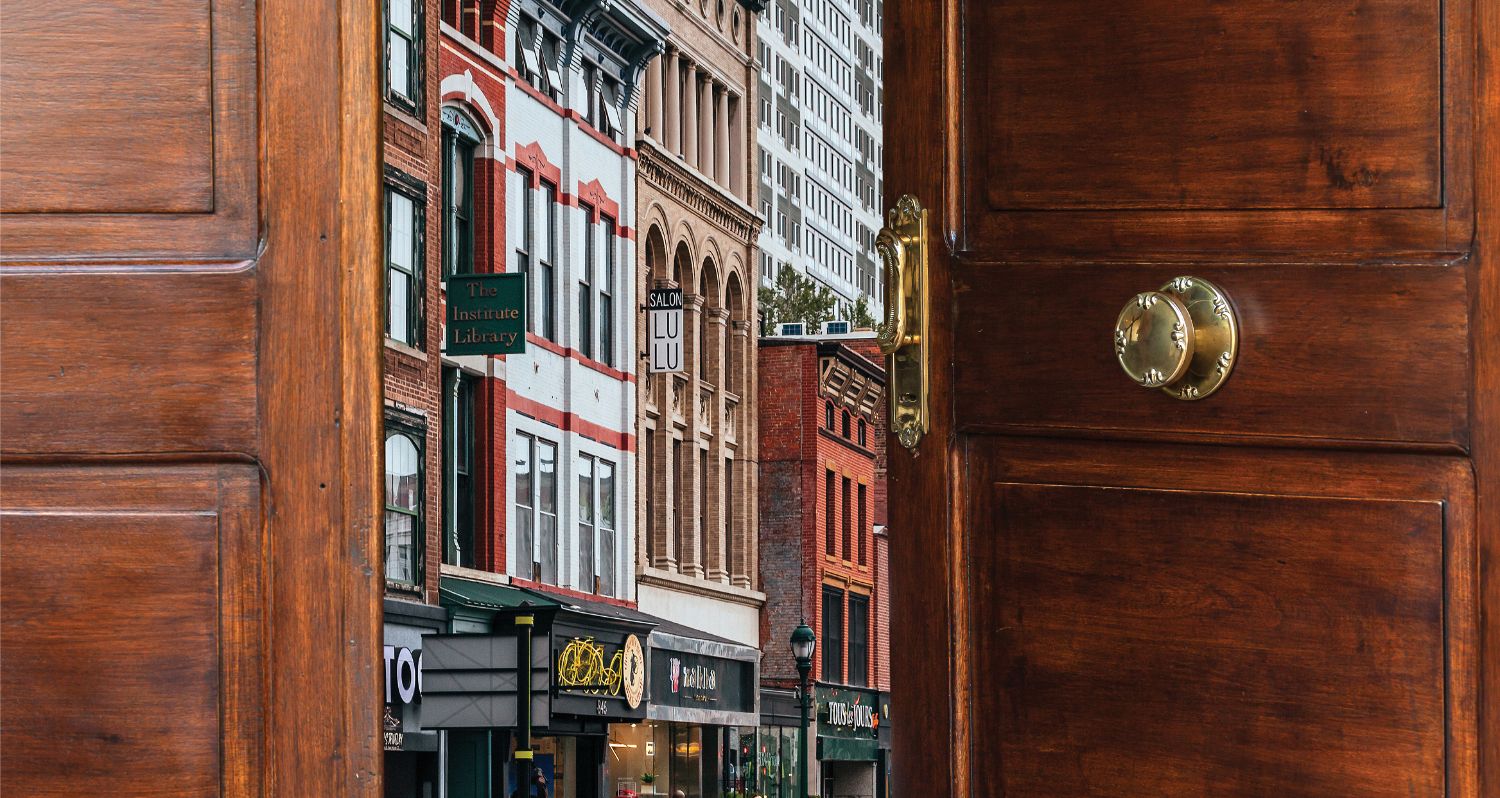 a door opening at ground level with a view of a city block with stores and apartments above them.