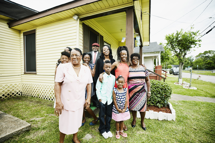 Portrait of smiling grandmother standing with family in front of house before going to church