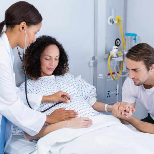 Doctor examining pregnant woman in ward of hospital